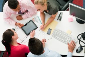 Four employees gathered around a digital tablet